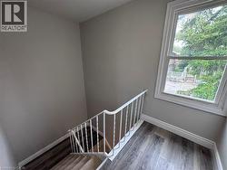 Stairwell featuring light gray wall paint, white trim, and a white metal railing - 