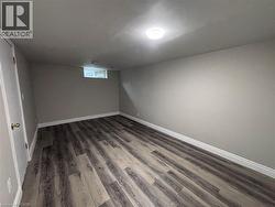 Finished room featuring wood-finish flooring, light gray walls, and white baseboards - 