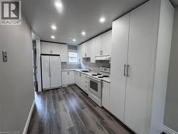 Contemporary kitchen featuring white cabinetry, gray wood-finish flooring, recessed lighting, white appliances, and a tiled backsplash - 