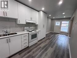 Modern kitchen area featuring white cabinetry, a stainless steel double-basin sink, and a white electric range - 