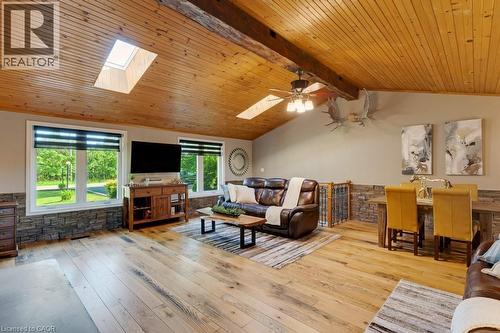 Spacious living area featuring a vaulted wood-paneled ceiling with exposed beams, wood-finish flooring, two skylights, and multiple windows - 3786 Old Beverly Road, North Dumfries, ON 
