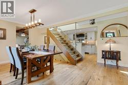 Hardwood flooring extends throughout this dining area, featuring a linear chandelier and crown molding - 