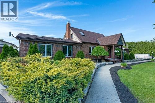Brick-clad residence featuring a covered front porch, multiple skylights, and a prominent chimney - 3786 Old Beverly Road, North Dumfries, ON 