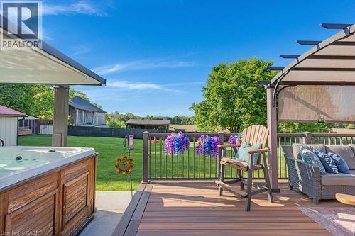 Expansive outdoor living area featuring a multi-level composite deck, a built-in hot tub with wood-finish paneling, and a pergola with retractable shades - 3786 Old Beverly Road, North Dumfries, ON 