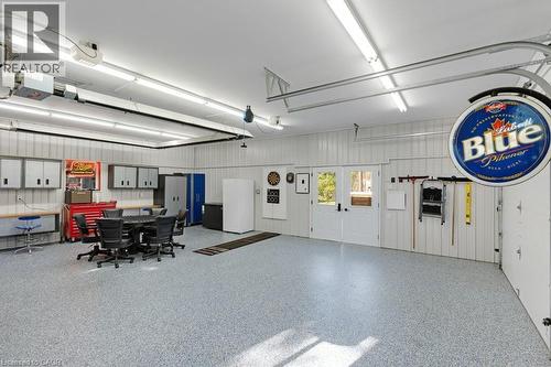 Spacious garage featuring a durable epoxy floor, ample overhead lighting, double exterior doors, and corrugated panel walls - 3786 Old Beverly Road, North Dumfries, ON 