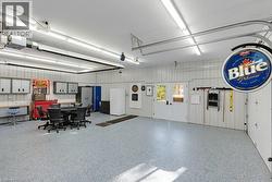 Spacious garage featuring a durable epoxy floor, ample overhead lighting, double exterior doors, and corrugated panel walls - 