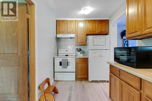 Apartment Kitchen featuring wood cabinetry, light-toned countertops, white tile backsplash, and light wood-finish flooring - 3786 Old Beverly Road, North Dumfries, ON 