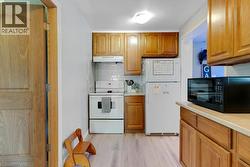 Apartment Kitchen featuring wood cabinetry, light-toned countertops, white tile backsplash, and light wood-finish flooring - 