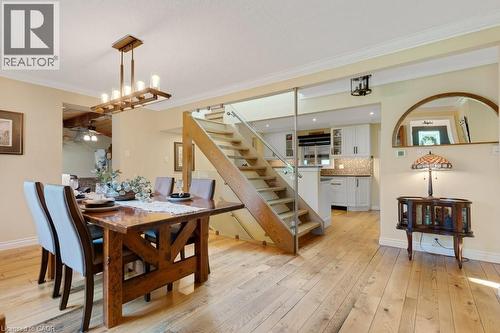 Hardwood flooring extends throughout this dining area, featuring a linear chandelier and crown molding - 3786 Old Beverly Road, North Dumfries, ON 