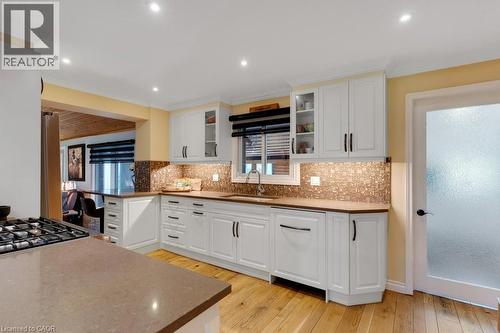 Kitchen featuring white Shaker-style cabinetry, wood-finish flooring, a mosaic tile backsplash, recessed lighting, and a built-in gas range - 3786 Old Beverly Road, North Dumfries, ON 
