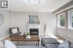 Bright living area featuring a fireplace with a white mantel, light wood-finish flooring, and multiple windows - 