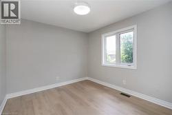 Neutral tone walls with wood-finish flooring, white trim, and a window with white casing - 