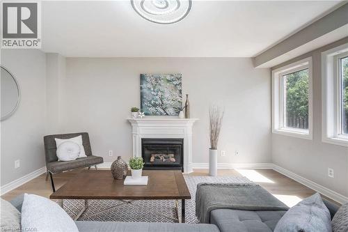 Bright living area featuring a fireplace with a white mantel, light wood-finish flooring, and multiple windows - 2425 Nichols Drive, Oakville, ON - Indoor Photo Showing Living Room With Fireplace