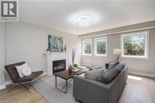 Living area featuring light-toned walls, wood-finish flooring, and a white mantel fireplace with a dark insert - 2425 Nichols Drive, Oakville, ON - Indoor Photo Showing Living Room With Fireplace