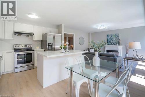 Open-concept living area featuring a modern kitchen with white cabinetry, stainless steel appliances, and light wood-finish flooring - 2425 Nichols Drive, Oakville, ON - Indoor Photo Showing Kitchen With Stainless Steel Kitchen With Upgraded Kitchen