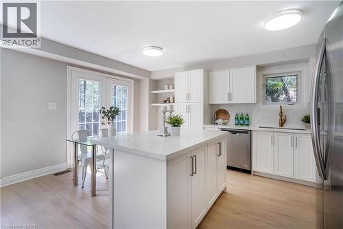 Kitchen featuring a central island, white cabinetry, integrated stainless steel appliances, light wood-finish flooring, and French doors - 2425 Nichols Drive, Oakville, ON - Indoor Photo Showing Kitchen