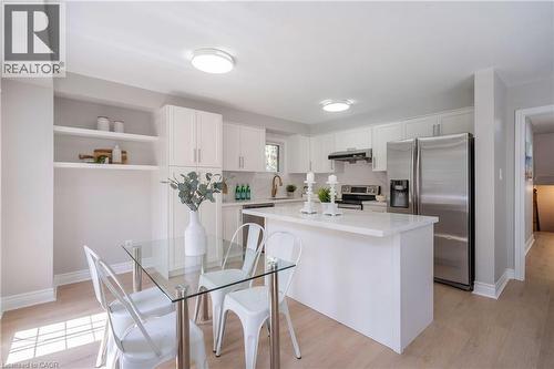 Bright kitchen featuring white cabinetry, a central island with a solid surface countertop, stainless steel appliances, and integrated shelving - 2425 Nichols Drive, Oakville, ON - Indoor