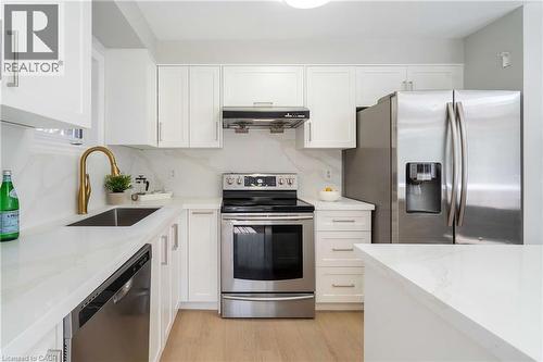 Modern kitchen featuring white cabinetry, stainless steel appliances, light wood-finish flooring, and white countertops with a matching backsplash - 2425 Nichols Drive, Oakville, ON - Indoor Photo Showing Kitchen With Stainless Steel Kitchen With Upgraded Kitchen