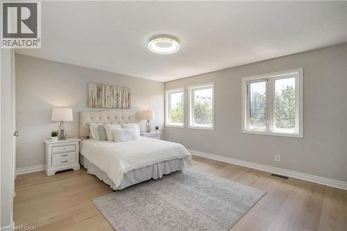 Spacious room featuring light wood-finish flooring and multiple windows with white trim - 2425 Nichols Drive, Oakville, ON - Indoor Photo Showing Bedroom