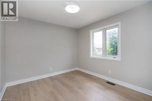 Neutral tone walls with wood-finish flooring, white trim, and a window with white casing - 2425 Nichols Drive, Oakville, ON - Indoor Photo Showing Other Room