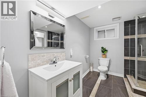 Bathroom featuring a white vanity with integrated sink, rectangular framed mirror, and a tiled shower enclosure with clear glass - 189 Foxbar Road, Burlington, ON 