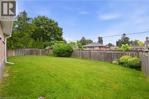 Expansive backyard featuring a manicured lawn, a full-perimeter wood fence, established shrubs, and mature trees - 189 Foxbar Road, Burlington, ON 