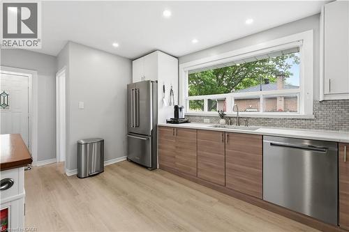 Kitchen featuring wood-finish lower cabinetry, white upper cabinetry, and light-toned countertops - 189 Foxbar Road, Burlington, ON 