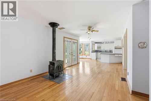 Open-concept interior featuring wood-finish flooring, a cast iron stove with a tiled hearth, and French doors - 3 Ancaster Street E, Dundas, ON - Indoor