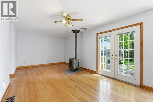 Open room with wood-finish flooring, a freestanding wood-burning stove on a stone-look hearth, and ceiling fan with integrated lighting - 3 Ancaster Street E, Dundas, ON - Indoor Photo Showing Other Room