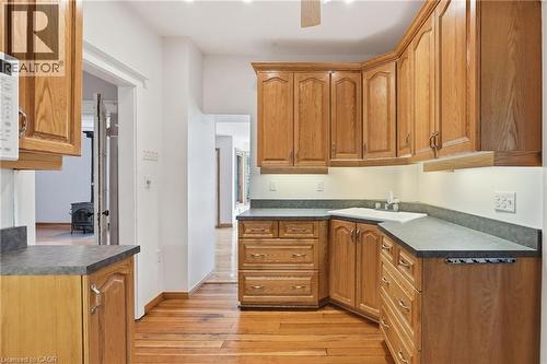 Kitchen featuring wood cabinetry, laminate countertops, a white sink, and wood-finish flooring - 3 Ancaster Street E, Dundas, ON - Indoor Photo Showing Kitchen