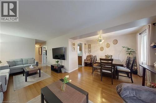 Open-concept living space featuring wood-finish flooring, recessed lighting, and a dining area with a chandelier - 233 Benesfort Crescent, Kitchener, ON 