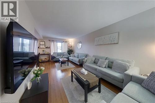 Expansive living area featuring warm wood-finish flooring, multiple windows with white curtains, neutral wall tones, and recessed lighting - 233 Benesfort Crescent, Kitchener, ON 