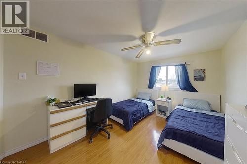 Bedroom featuring wood-finish flooring, a ceiling fan with integrated lighting, and a window with a white frame - 233 Benesfort Crescent, Kitchener, ON 