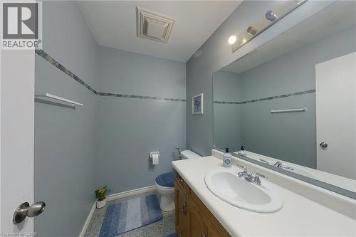 Bathroom featuring a wood-finish vanity with an integrated sink and laminate countertop - 233 Benesfort Crescent, Kitchener, ON 