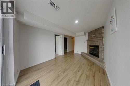 Spacious room featuring wood-finish flooring and a corner brick-clad fireplace with a raised hearth - 233 Benesfort Crescent, Kitchener, ON 