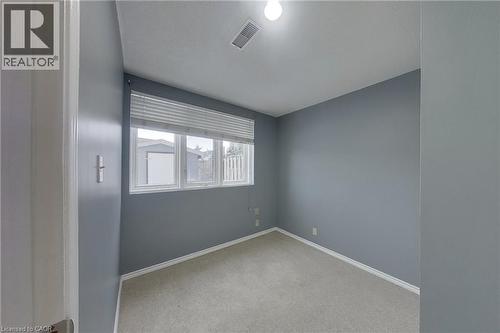 Carpeted room featuring light gray walls, a window with blinds, baseboard trim, and a ceiling light fixture - 233 Benesfort Crescent, Kitchener, ON 