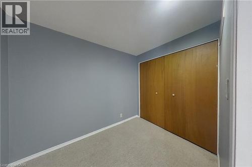 Room featuring neutral wall paint, light-toned carpet, and a bi-fold closet with wood-finish doors - 233 Benesfort Crescent, Kitchener, ON 