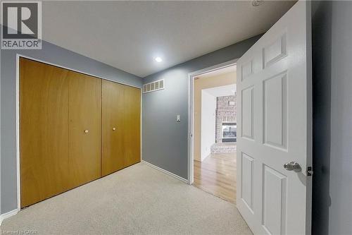 Carpeted room with wood-finish bi-fold closet doors and neutral gray walls - 233 Benesfort Crescent, Kitchener, ON 