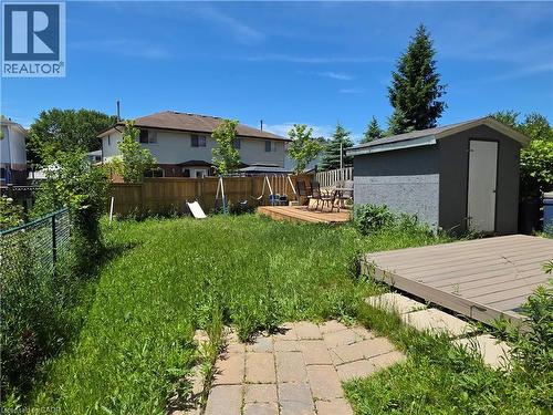 Backyard featuring a wooden privacy fence, a raised wood-finish deck, a paved stone patio, a storage shed, and a composite material deck section - 233 Benesfort Crescent, Kitchener, ON 