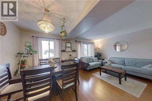 Open-concept living and dining area featuring wood-finish flooring, recessed lighting, and a prominent chandelier - 233 Benesfort Crescent, Kitchener, ON 