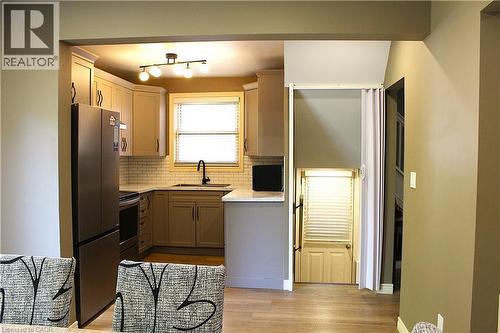 Kitchen featuring light wood-finish cabinetry, white subway tile backsplash, and stainless steel appliances - 4935 Willmott Street, Niagara Falls, ON 