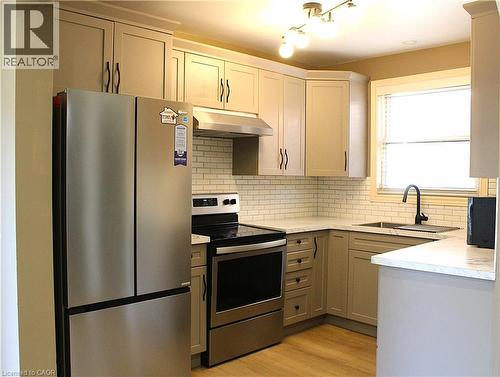 Kitchen featuring light-toned cabinetry with dark hardware, stainless steel appliances, a white subway tile backsplash, and light wood-finish flooring - 4935 Willmott Street, Niagara Falls, ON 