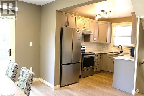 Contemporary kitchen featuring stainless steel appliances, light-toned cabinetry, subway tile backsplash, and wood-finish flooring - 4935 Willmott Street, Niagara Falls, ON 