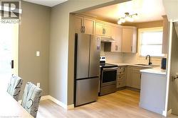 Contemporary kitchen featuring stainless steel appliances, light-toned cabinetry, subway tile backsplash, and wood-finish flooring - 