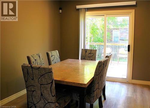 Dining area featuring wood-finish flooring, neutral wall tones, white baseboards, and a sliding glass door providing access to a wooden deck - 4935 Willmott Street, Niagara Falls, ON 