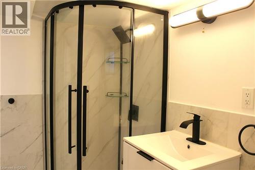 Contemporary bathroom featuring a curved glass shower enclosure with matte black framing and hardware - 4935 Willmott Street, Niagara Falls, ON 