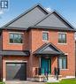 Brick facade featuring dark gray siding accents and a contrasting teal front door - 279 Hess Street S, Hamilton, ON  - Outdoor With Exterior 