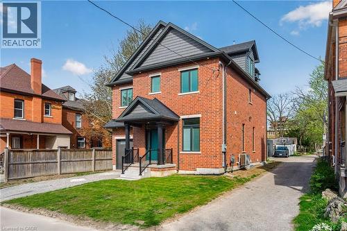 Contemporary brick exterior featuring a multi-level roofline, prominent front porch with black railings, and an integrated single-car garage - 279 Hess Street S, Hamilton, ON - Outdoor