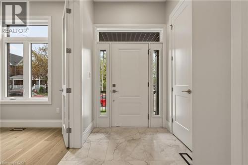 Bright entryway featuring a white paneled door with sidelights and transom window, light-toned marble-look tile flooring, and a built-in storage closet - 279 Hess Street S, Hamilton, ON - Indoor Photo Showing Other Room