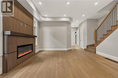 Living area featuring a floor-to-ceiling wood slat accent wall with a linear electric fireplace and dark wood mantel - 279 Hess Street S, Hamilton, ON - Indoor Photo Showing Other Room With Fireplace